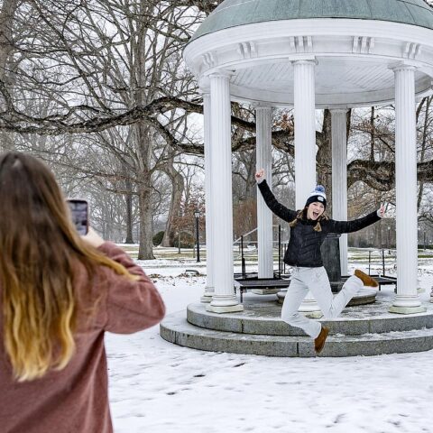 A person jumps in front of the Old Well while posing for a photo on the UNC-Chapel Hill campus.