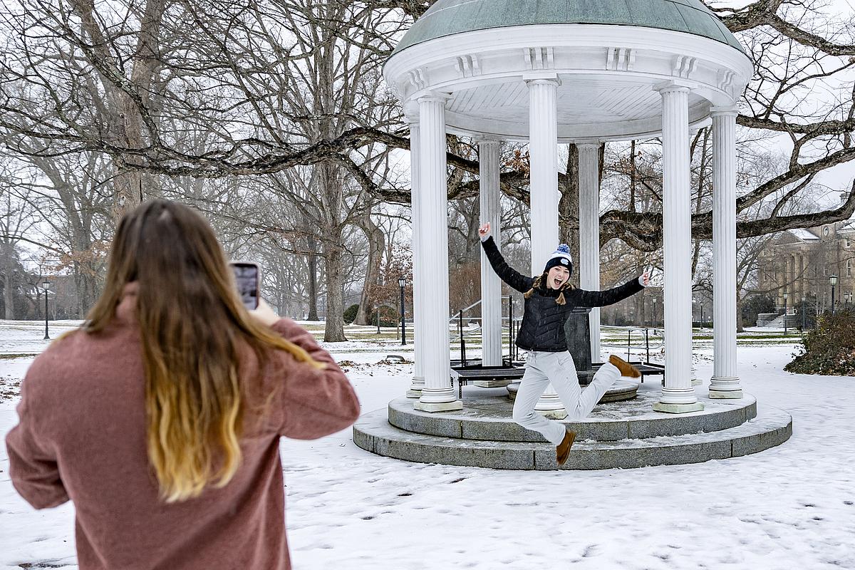 A person jumps in front of the Old Well while posing for a photo on the UNC-Chapel Hill campus.